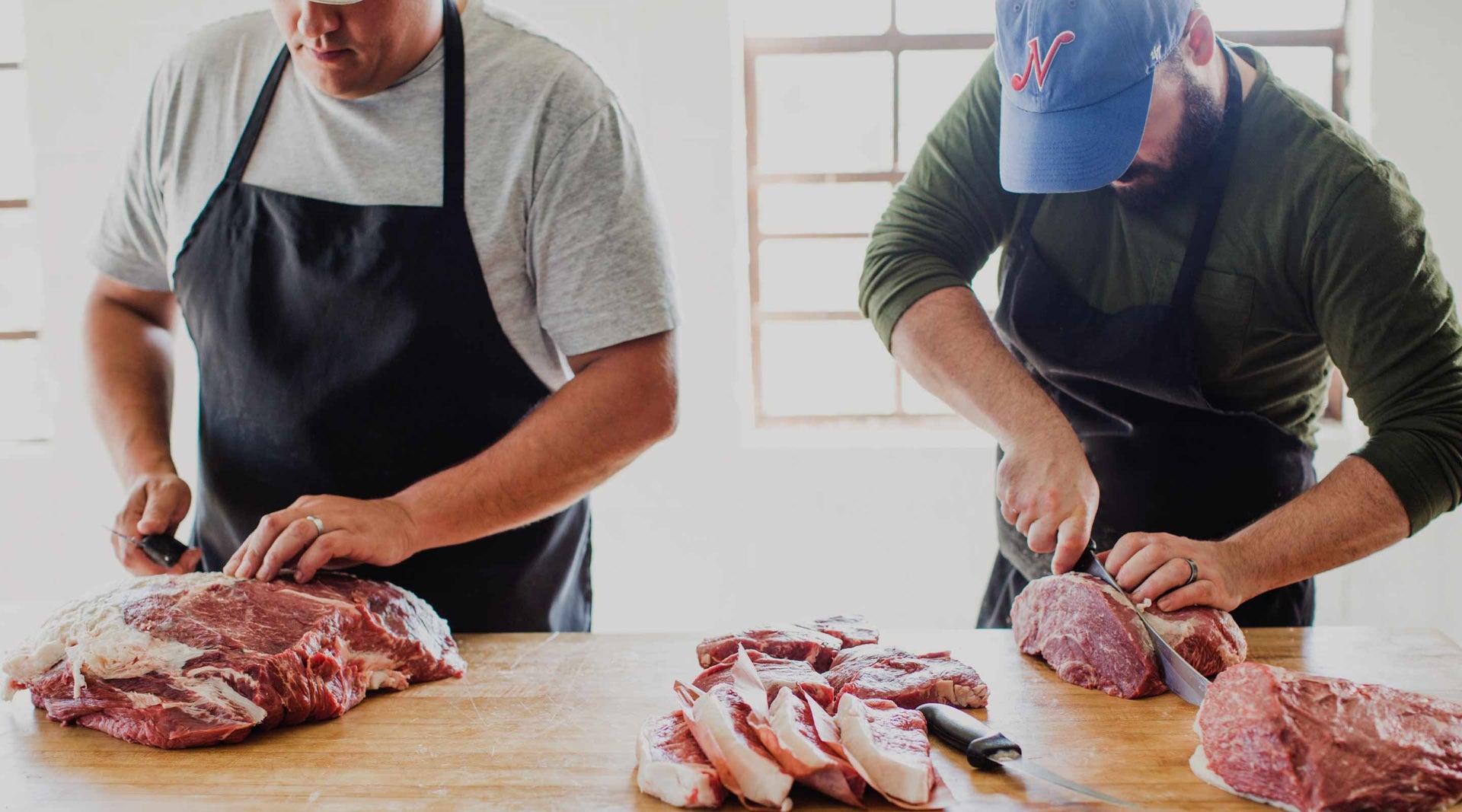 Founders Chris Carter and James Peisker cutting steaks at butcher block